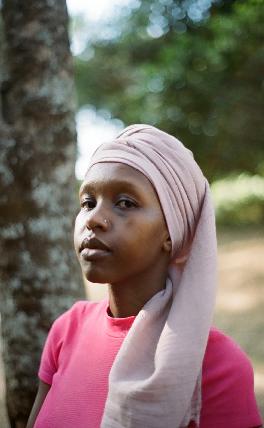 Photo portrait of young African woman wearing pink head scarf and top.