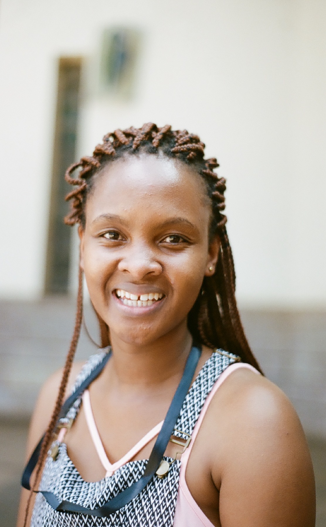 Photo portrait of young African woman smiling with braids and a patterned dungary