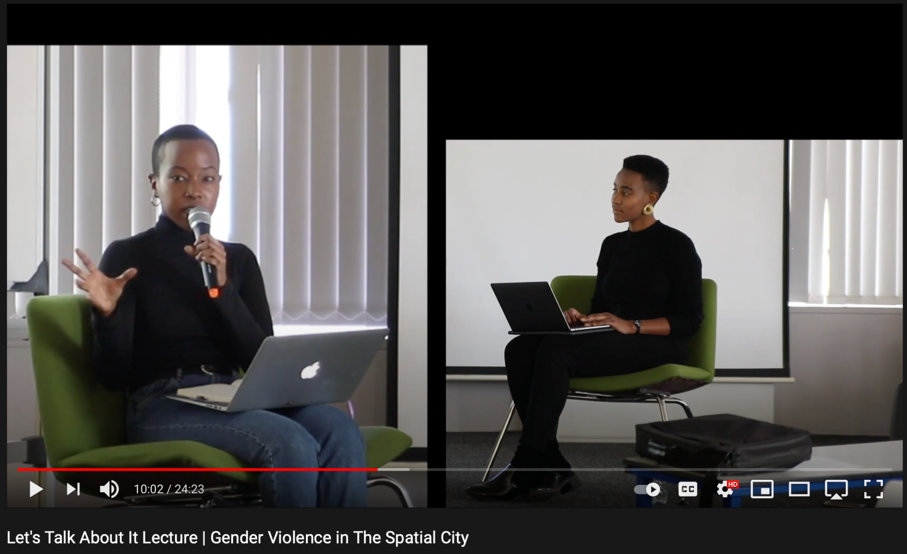 Film still showing Aisha Mugo and Khensani Jurczok-de Klerk sitting on chairs. Aisha is speaking into a microphone in dialogue on a stage.