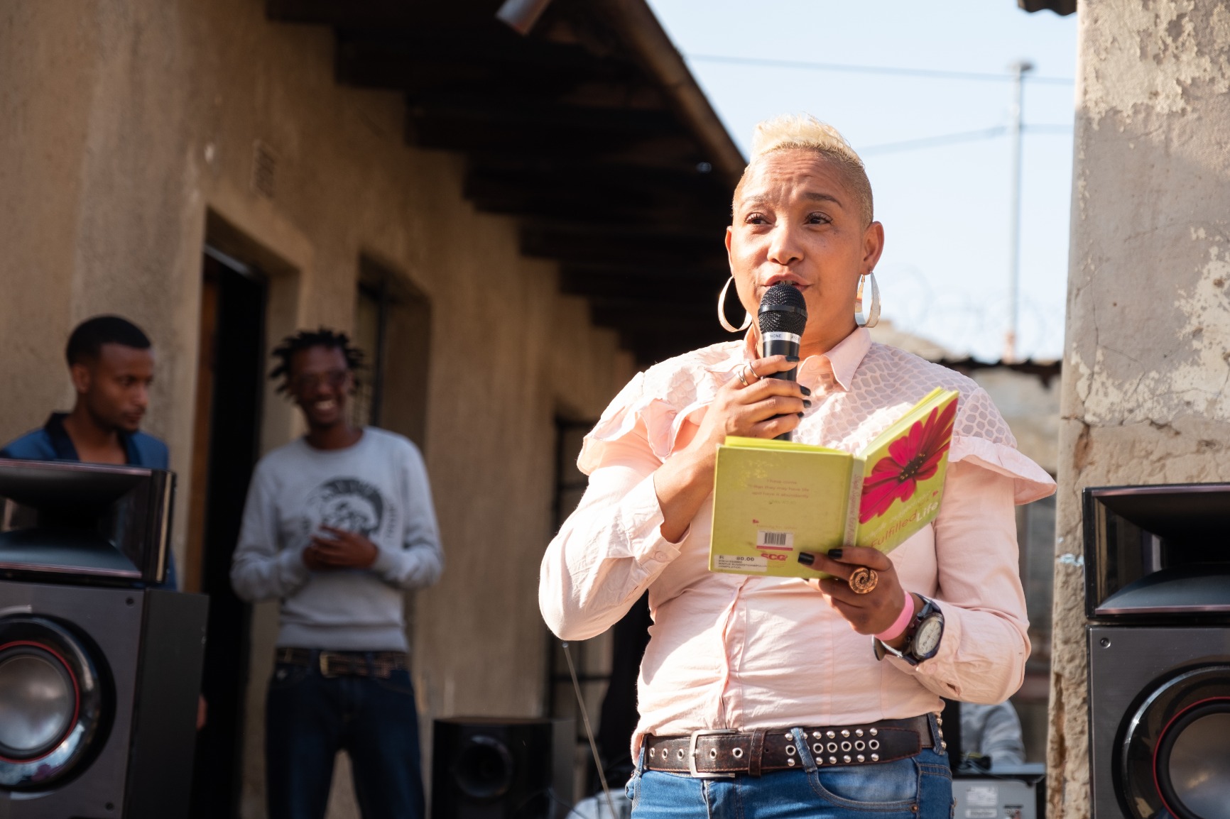 Photo of one of the Westbury women residents giving a talk in the courtyard, holidng a book